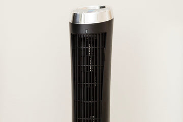 A tall tower cooling fan with a black vent facing frontwards and a silver top.